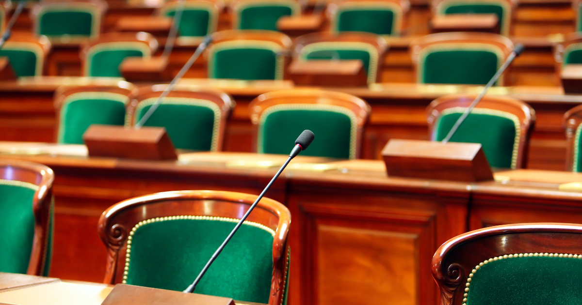 Empty seats with microphones in a legislative chamber, symbolizing the US House Agriculture Committee's move to redefine hemp in the draft 2024 Farm Bill, potentially banning products like delta-8 THC and THCA, sparking regulatory debates.