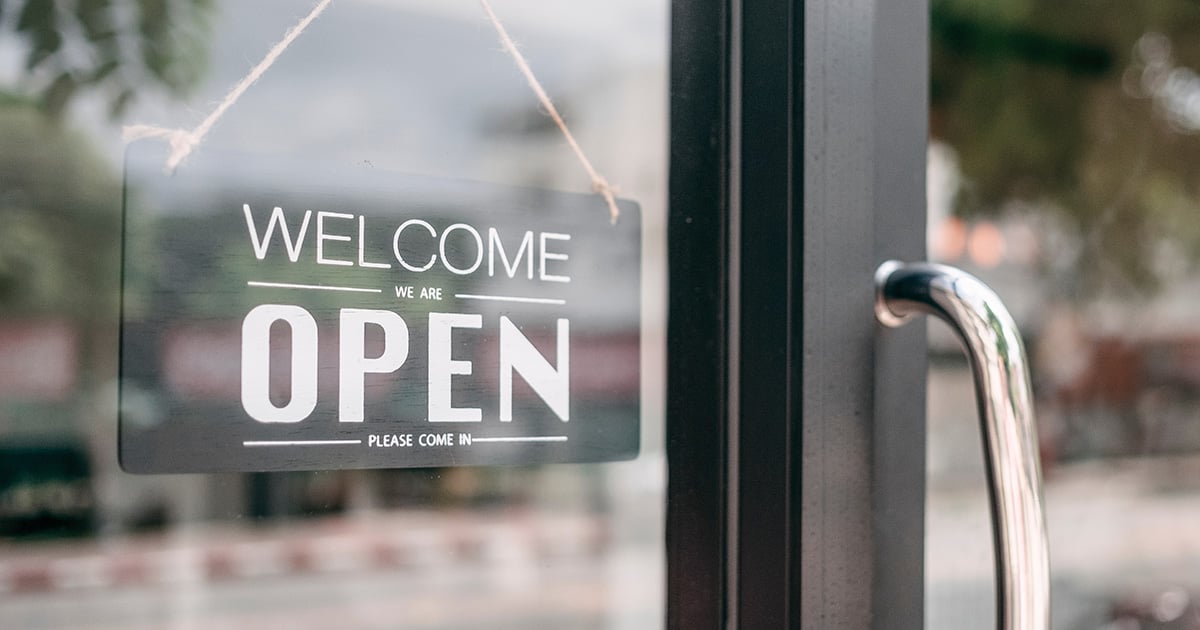 Welcome sign on a glass door invites entry, symbolizing a successful cannabis business guided by the strategic insights from CannaSpyglass, as detailed in the eBook 'Building a data-backed cannabis business plan'.